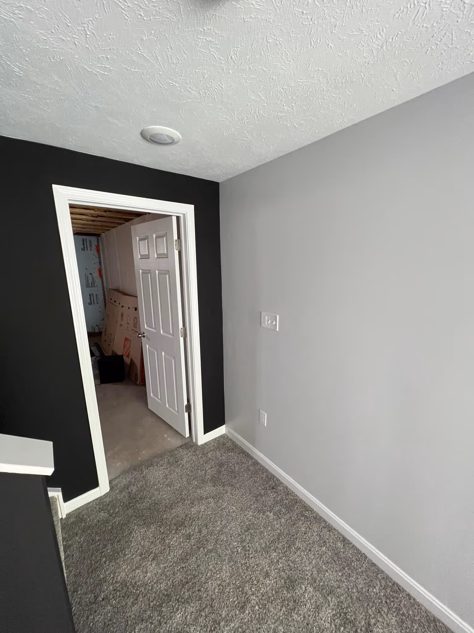 Interior view of a room with wooden floor, white staircase with dark brown railing, and an adjacent kitchen.
